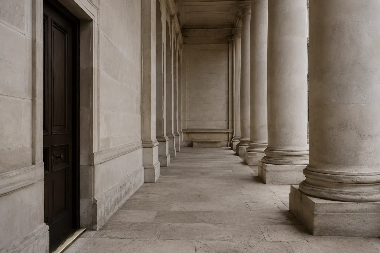 Monumental walnut doors framed in pale limestone and aged brass